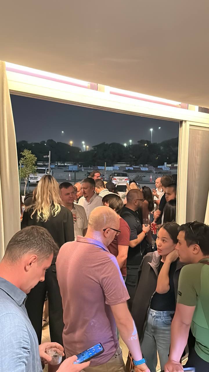 An evening reception, the room full and the terrace doors open behind